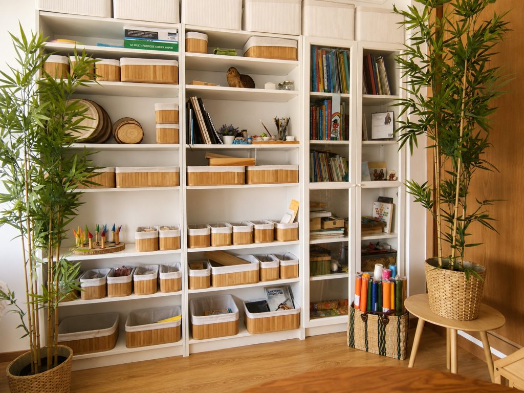 Ateliê da AKSHARA com materiais criativos, livros, peças em madeira e plantas.